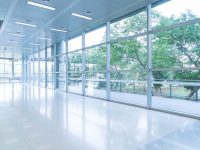 Blurred abstract background interior view looking out toward to empty office lobby and entrance doors and glass curtain wall with frame - blue white balance processing style